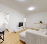 Wohnzimmer in einer 3-Zimmer-Wohnung mit Sofa, Fernseher und Holzboden.