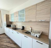Küchenzeile mit weißen Schränken und Bodenbelag in Holzoptik in einer 3-Zimmer-Wohnung.
