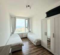 Ein Zimmer mit zwei Betten und einem Schrank, Holzboden in einer 3-Zimmer-Wohnung.