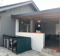 Ein Einfamilienhaus in Čaňa in der SNP-Straße mit Terrasse, Pflastersteinen und einem eingezäunten Auslauf für den Hund.