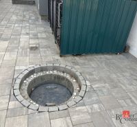 Entlang der Betonpflastersteine des Einfamilienhauses in der SNP-Straße in Čaňa befindet sich ein runder Schachtdeckel.