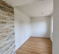 Ein Raum in einem Einfamilienhaus mit einem Holzboden und einer Wandverkleidung aus Stein.