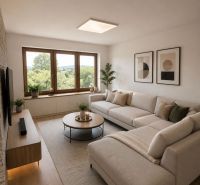 Wohnzimmer in einem Einfamilienhaus mit Sofa, Tisch und Boden in Holzoptik.
