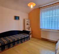 Wohnzimmer im Einfamilienhaus mit Sofa, Regal und Vorhang am Fenster.