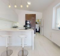 Eine Küche in einer 3-Zimmer-Wohnung mit einer Insel, Barhockern und weißen Schränken.