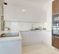 Eine Küche mit weißen Schränken, eingebauten Geräten und einem Boden in Holzoptik in einer 3-Zimmer-Wohnung.