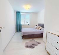 Helles Schlafzimmer mit Holzdekorboden, Doppelbett und weißer Kommode in einer 3-Zimmer-Wohnung.