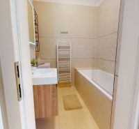 Ein Badezimmer mit Badewanne und Heizkörper in einer 3-Zimmer-Wohnung, in einer weißen und beigen Ausführung.