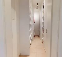 Ein enger Flur mit eingebauten Regalen in einer 3-Zimmer-Wohnung.