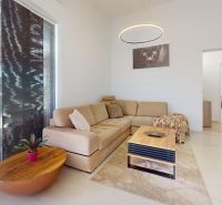 Wohnzimmer mit cremefarbenem Sofa, hellem Boden in Holzoptik und stilvollem Tisch.