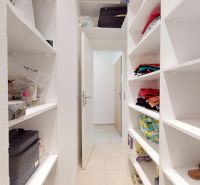 Ein weißer Abstellraum mit eingebauten Regalen in einer 3-Zimmer-Wohnung, voll mit verschiedenen Gegenständen.