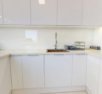 Eine Küchenzeile in einer 3-Zimmer-Wohnung mit weißen Schränken und einer grünen Kletterpflanze.