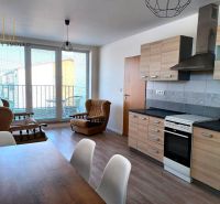 Wohnzimmer mit Sofas, Küchenzeile und Holzboden in einer Zweizimmerwohnung.