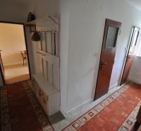 Ein schmaler Flur in einer 2-Zimmer-Wohnung, mit rotem Teppich und einer Garderobe an der Wand.
