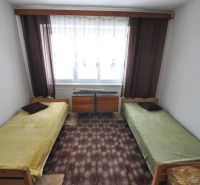 Schlafzimmer mit zwei Einzelbetten, Teppich und Fenster in einer Zweizimmerwohnung.