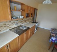Küche in einer 2-Zimmer-Wohnung mit Holzschränken und Fliesenverkleidung.