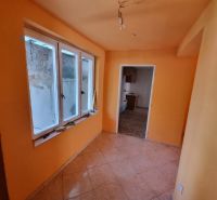 Ein orange gestrichener Flur mit Fenstern und Fliesen, der in einen weiteren Raum in einem Einfamilienhaus führt.
