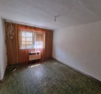 Ein Zimmer in einem Einfamilienhaus mit Boden und Fenstern mit Vorhängen.