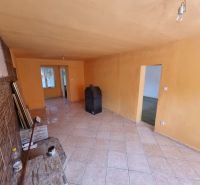 Wohnzimmer in einem Einfamilienhaus mit orangefarbenen Wänden und Fliesenboden.