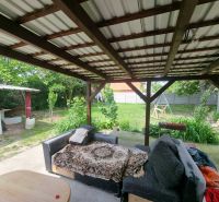 Die Veranda des Einfamilienhauses in der Šípošová-Straße in Šahy mit einem Sofa und einem Garten.