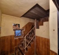 Innenraum eines Einfamilienhauses mit einer Metalltreppe, abgenutzten Wänden und einem Fenster mit Tapete.