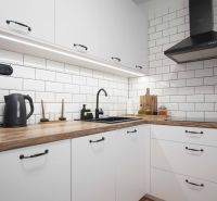 Weiße Küchenzeile mit Holzboden in einer 2-Zimmer-Wohnung.
