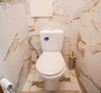 Toilette im Badezimmer mit Marmorfurnier in einer 2-Zimmer-Wohnung.