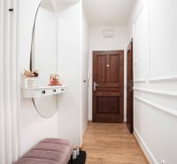 Der Flur einer 2-Zimmer-Wohnung mit einem Boden in Holzoptik und einem Spiegel an der Wand.
