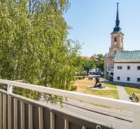 Blick vom Balkon in Nové Zámky, in der Nähe einer 2-Zimmer-Wohnung, mit Kirche und Grün.