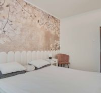 Schlafzimmer in einer 2-Zimmer-Wohnung mit Wanddekoration aus Blumen und hellen Möbeln.