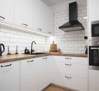 Küche in einer 2-Zimmer-Wohnung mit weißen Schränken und einem Boden in Holzoptik.