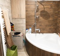 Badezimmer in einer 3-Zimmer-Wohnung mit Badewanne und Fliesendekor in Holzoptik.