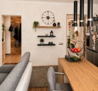 Innenraum einer 3-Zimmer-Wohnung mit Holzboden, bequemen Sitzgelegenheiten und Regalen.