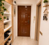 Eingang in eine 3-Zimmer-Wohnung mit Ziegelwand und Boden in Holzoptik.