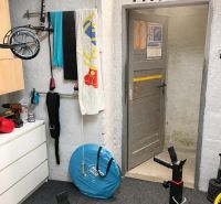 Fitness-Ecke mit Krafttrainingsgerät und Aufbewahrungselementen, geeignet für eine 3-Zimmer-Wohnung.