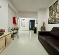 Empfangsbereich in Geschäftsräumen mit dunklem Sofa und Blumendekorationen.