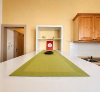 Küchenzeile mit Holzschränken und grüner Tischdecke in einer Einzimmerwohnung.