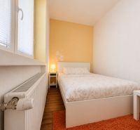 Schlafzimmer in einer Einzimmerwohnung mit Holzdekorboden und orangem Teppich.