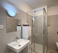 Badezimmer mit Dusche, Spiegel und Waschbecken in einer 2-Zimmer-Wohnung.