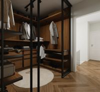 Ein Kleiderschrank im Einfamilienhaus mit Regalen, Spiegeltüren und einem Boden in Holzoptik.