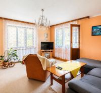 Wohnzimmer mit cremefarbenen Wänden, einem orangefarbenen Sessel und einem grauen Sofa in einem Einfamilienhaus.