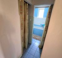 Badezimmer im Einfamilienhaus mit blauer Badewanne und Vorhängen, Fliesen auf dem Boden.