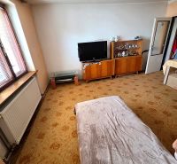 Wohnzimmer in einem Einfamilienhaus mit Fernseher, Vitrinen und dekorativem Teppich.