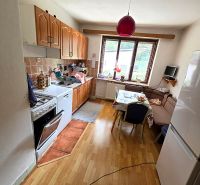 Küche mit Holzelementen, Gasherd, Kühlschrank und Esstisch in einem Einfamilienhaus.