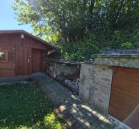 Ein Holzunterstand und ein Steingebäude im Garten eines Einfamilienhauses in Mikušovce.