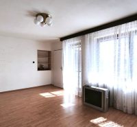 Wohnzimmer in einem Einfamilienhaus mit Holzboden und großen Fenstern mit Vorhängen.