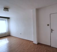 Ein geräumiges Zimmer in einem Einfamilienhaus mit einem Holzboden und einem großen Fenster.