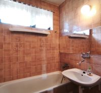Badezimmer eines Einfamilienhauses mit Badewanne, Waschbecken und gefliesten Wänden in einem braunen Farbton.