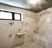 Badezimmer mit Fliesen, Waschbecken und Badewanne in einem Einfamilienhaus.