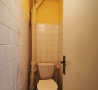 Ein kleines, schmales WC mit Fliesen in einem Einfamilienhaus mit weißen Kacheln.